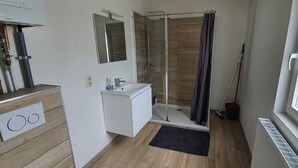 Un baño moderno con ducha, lavabo y espejo.