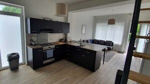 Una cocina moderna con armarios oscuros, una isla central y un ventanal grande.