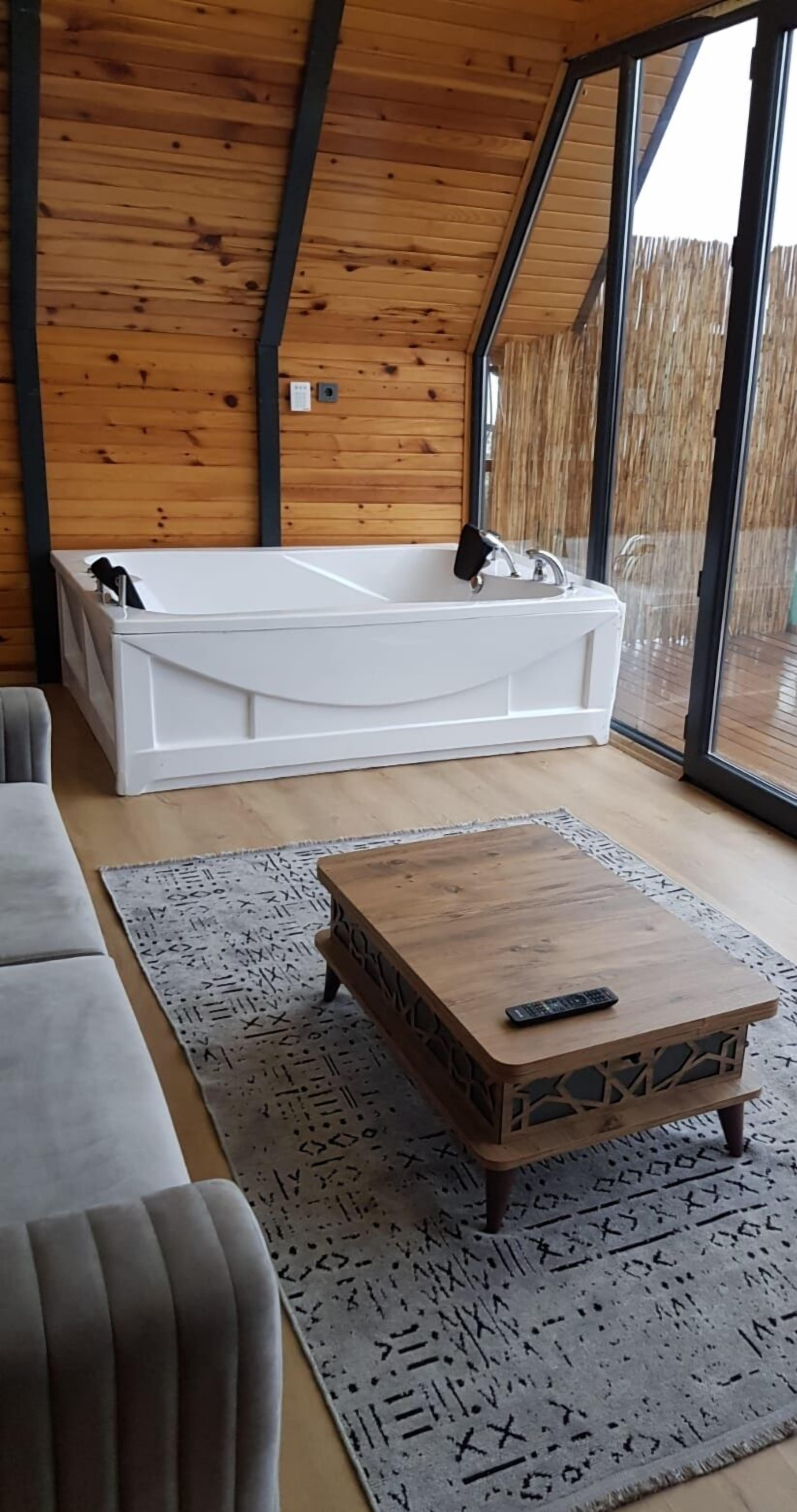 Un interior moderno con una bañera blanca, una mesa de centro de madera y una alfombra estampada.