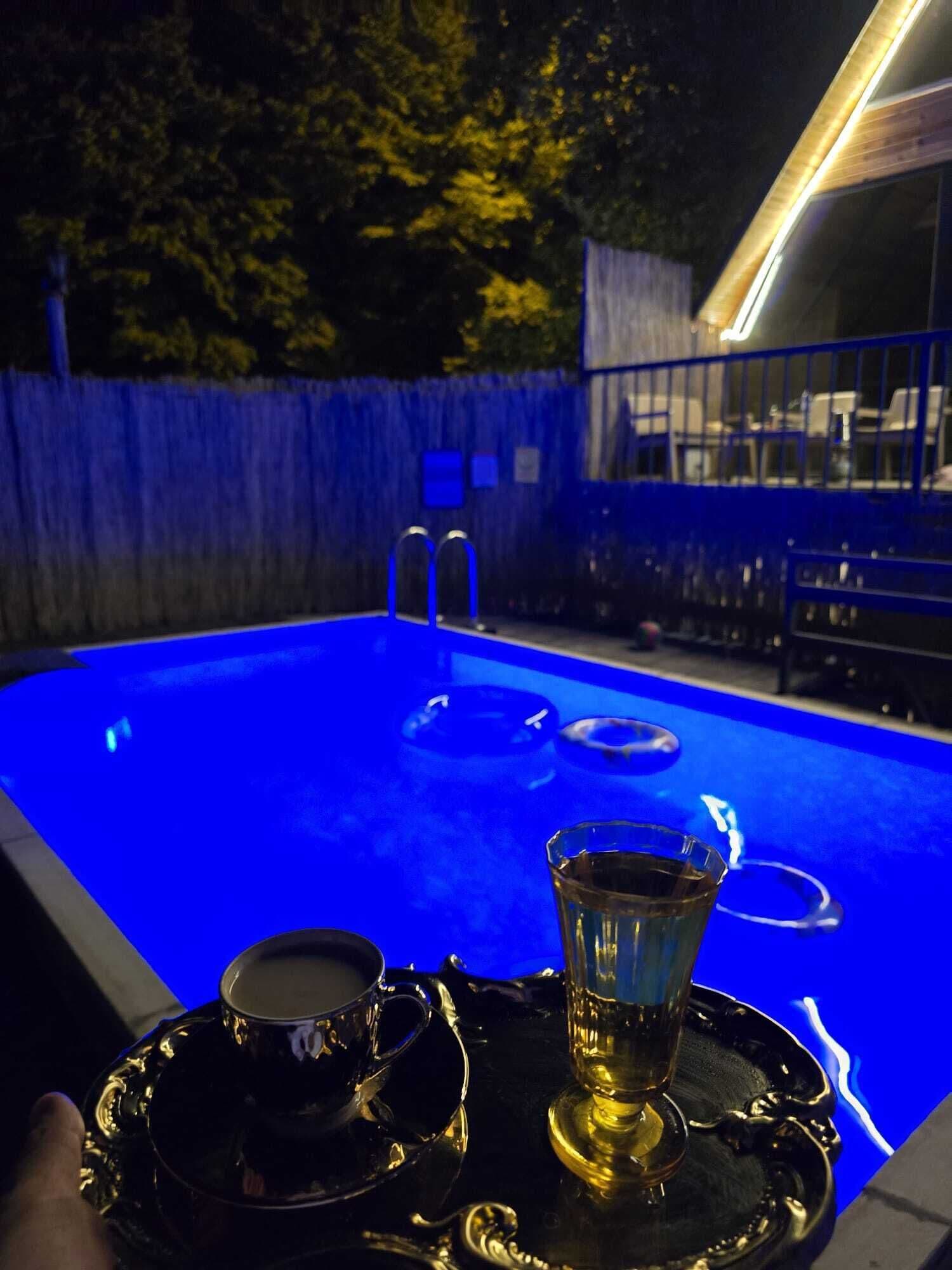 A pool area with a glass table set with a teapot, cup, and saucer.
