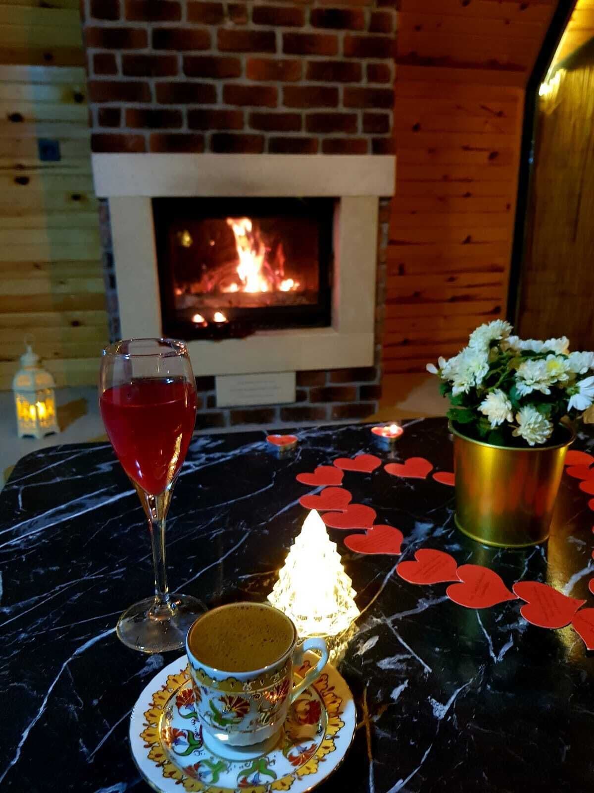 A table with a glass of red wine, a cup of coffee, and a candle.
