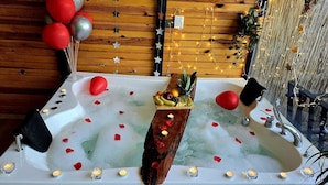 Un bain à remous décoré de pétales de rose, de bougies et de fruits.