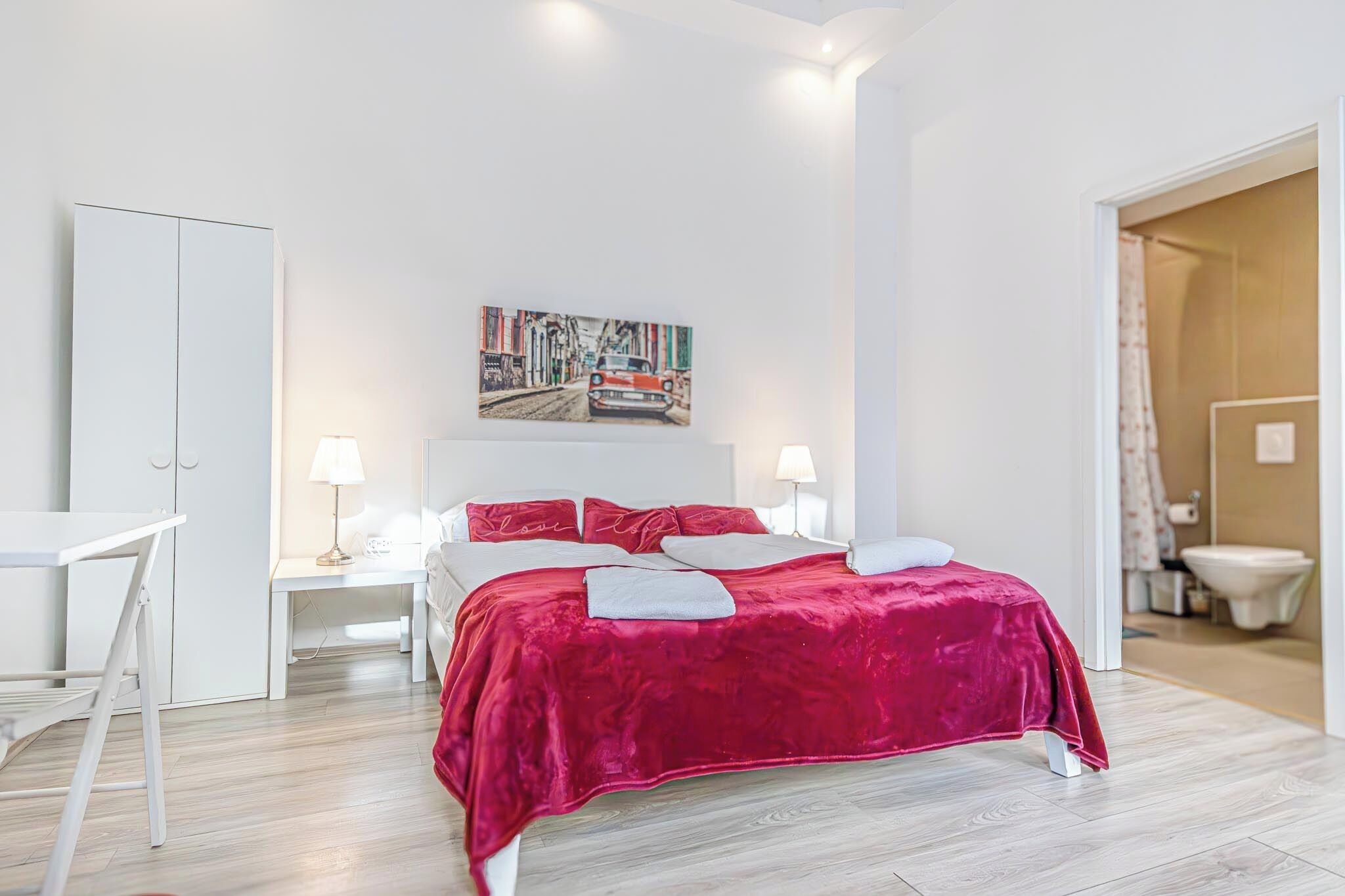 Une chambre moderne avec un grand lit, un bureau et un tableau accroché au mur.
