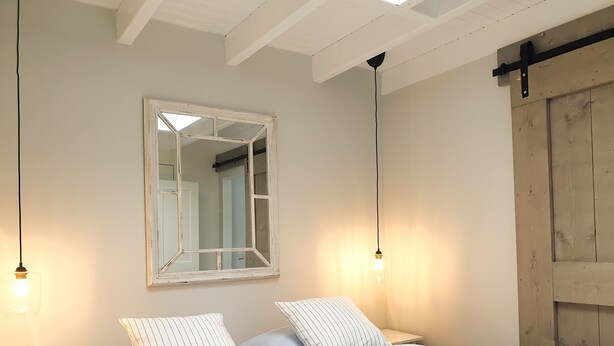 Un dormitorio con una cama, dos mesitas de noche, un espejo y una puerta de madera.