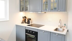 Una cocina moderna con gabinetes grises, un lavamanos de acero inoxidable y un salpicadero de azulejos.