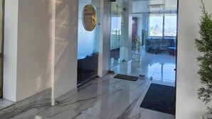 Un vestíbulo amplio con piso de mármol, una recepción y un gran ventanal con vistas al interior.