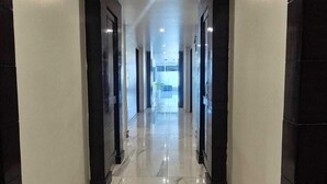 Un pasillo largo y estrecho con suelo de mármol y columnas de madera oscura.