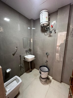 A bathroom with a toilet, bidet, sink, and a shower area. - The Vrnda Heritage (Haridwar)