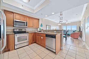 A modern kitchen with wooden cabinets, stainless steel appliances, and a large island. - Seawind 1506 | Beachfront Condo – Great location - walk to everything! (Gulf Shores)