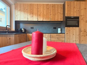 A kitchen with wooden cabinets, a black oven, and a red candle on a plate.