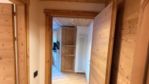 A hallway with wooden doors and a kitchen area visible in the background. - Apartment 'Stella' with Mountain View, Private Terrace and Wi-Fi (Isolaccia)