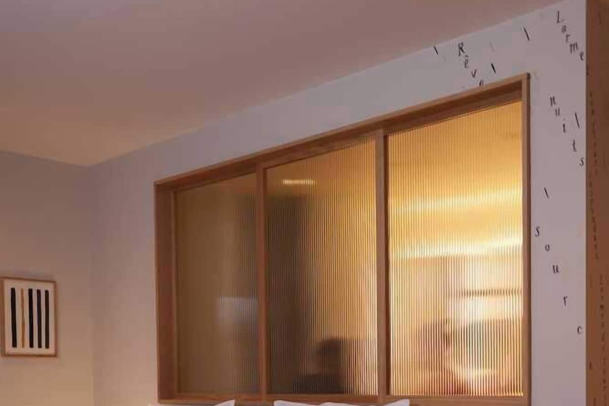 A modern bedroom with a large bed, a bedside table, and a window with blinds.