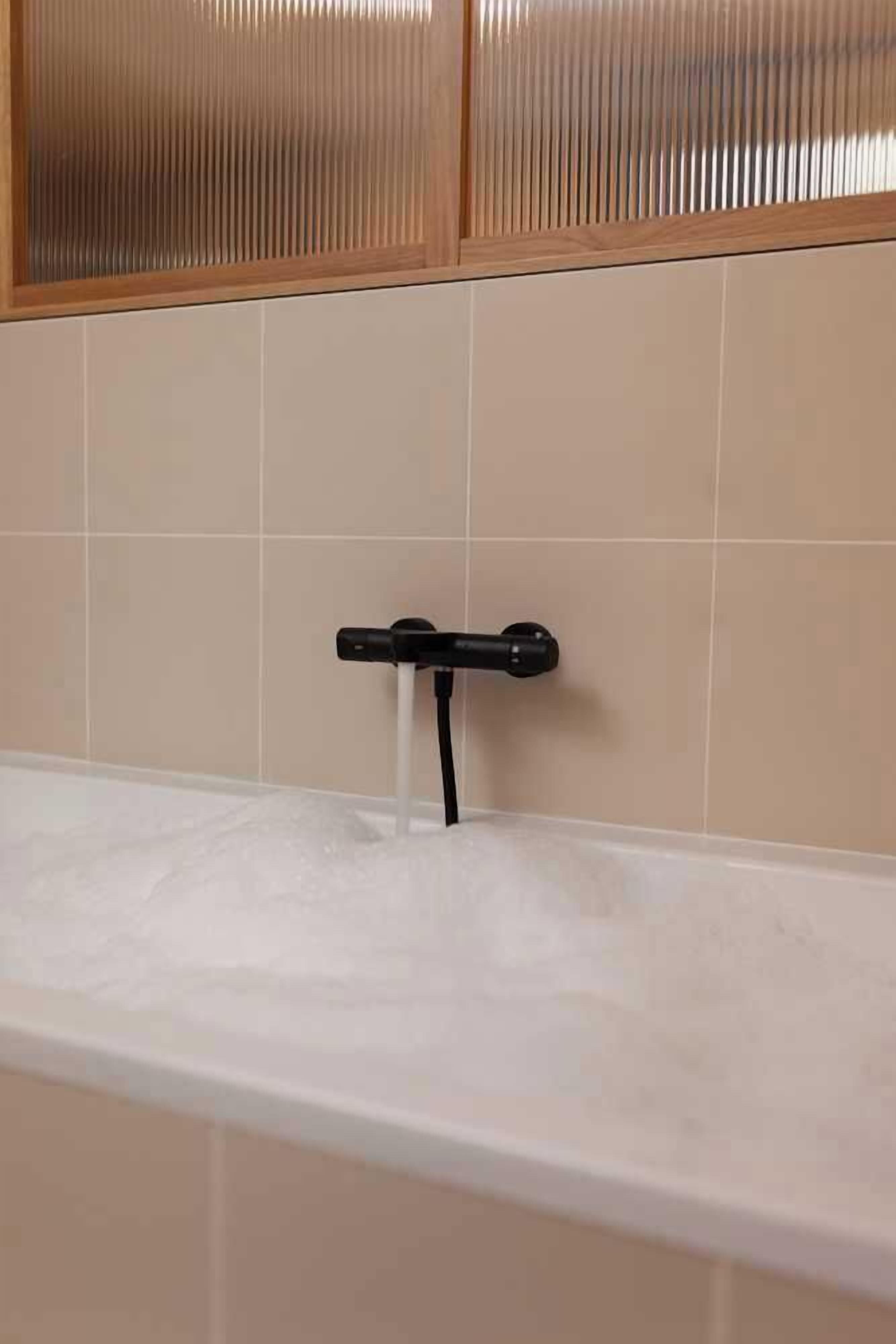 A bathroom with a bathtub, a faucet, and a towel rack.