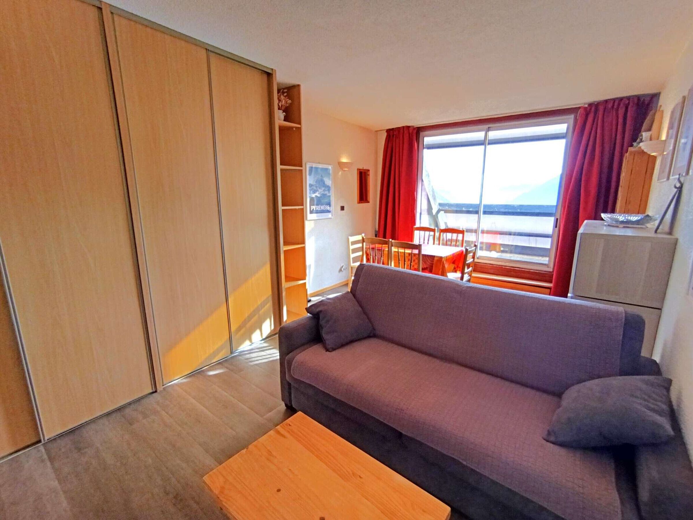 A living room with a sofa, a wooden coffee table, a dining area with a table and chairs, and a view of the sea through large windows.