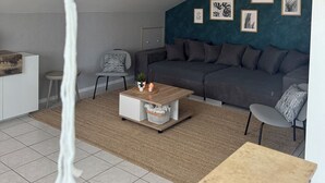 Un saló modern amb una paret d'accent blau fosc, un sofà gris, una taula de centre de fusta i una planta penjant.
