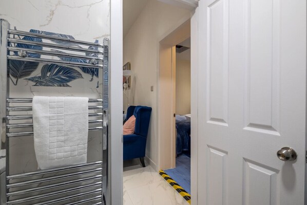 Ein Badezimmer mit Handtuchhalter, Dusche und einer Tür zum Schlafzimmer.