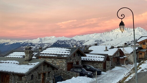 Un village de montagne enneigé, avec des bâtiments en pierre et un lampadaire.