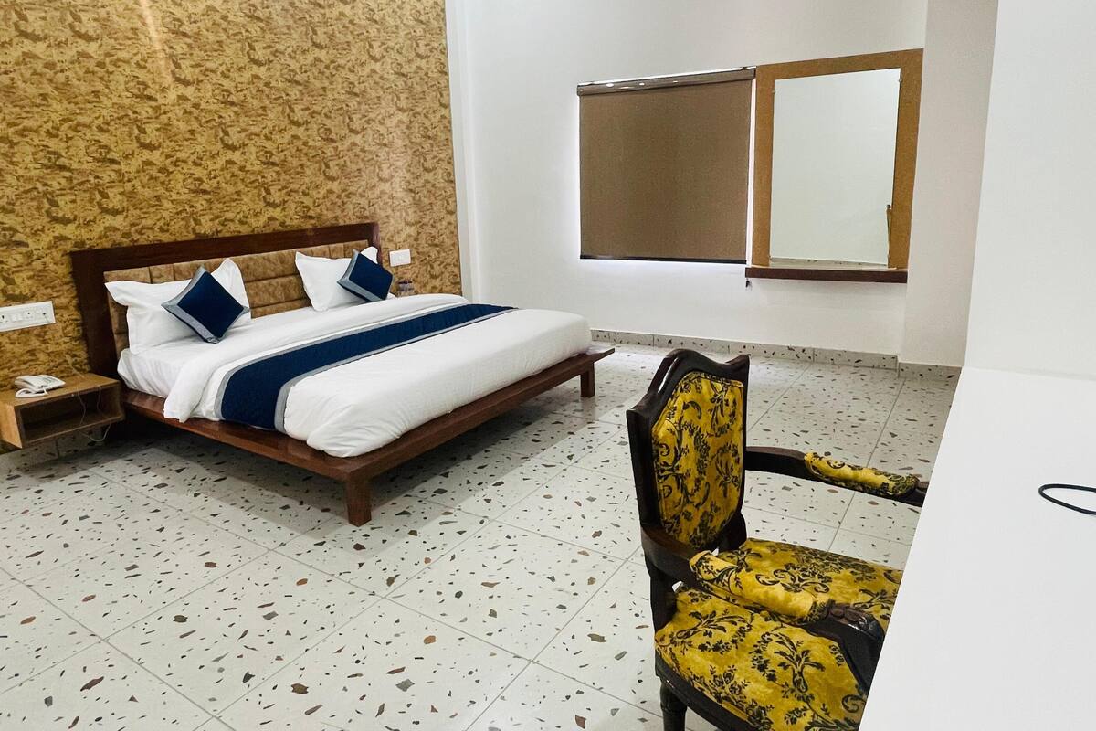 Habitación de hotel con cama, mesita de noche, una silla, ventana y pared con diseño decorativo.