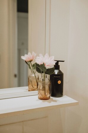 A bathroom vanity with a mirror, a vase with flowers, and a hand soap dispenser. - The Kentish Tasmania (Oatlands)