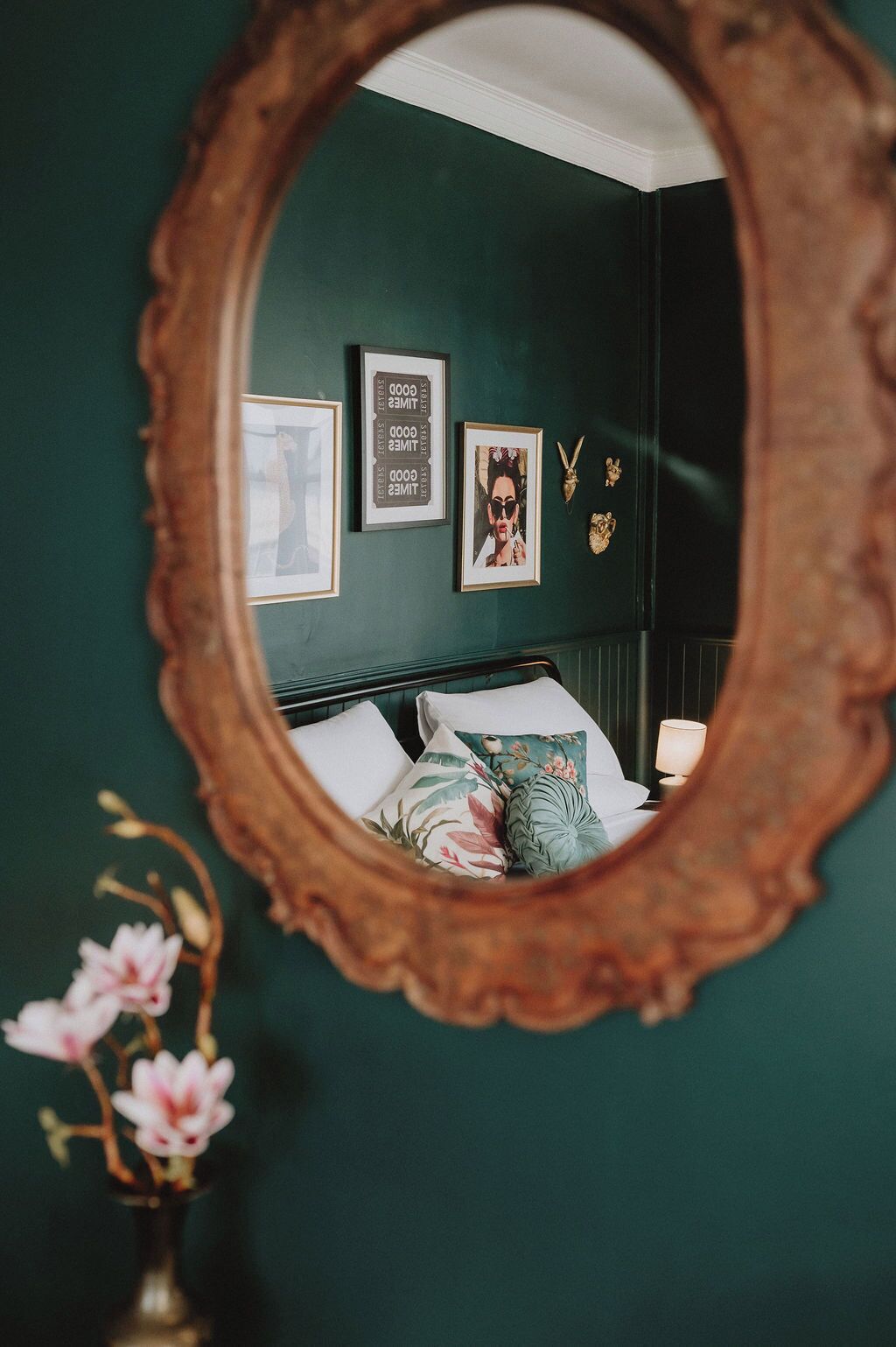 Un dormitorio con cama, espejo y decoración en la pared.