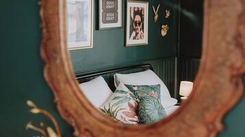 Un dormitorio con cama, espejo y decoración en la pared.