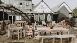 A rustic outdoor seating area with wooden tables and chairs, a child, and an adult. - The Kentish Tasmania (Oatlands)