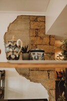 Una pared de piedra rústica con un estante que exhibe objetos decorativos.