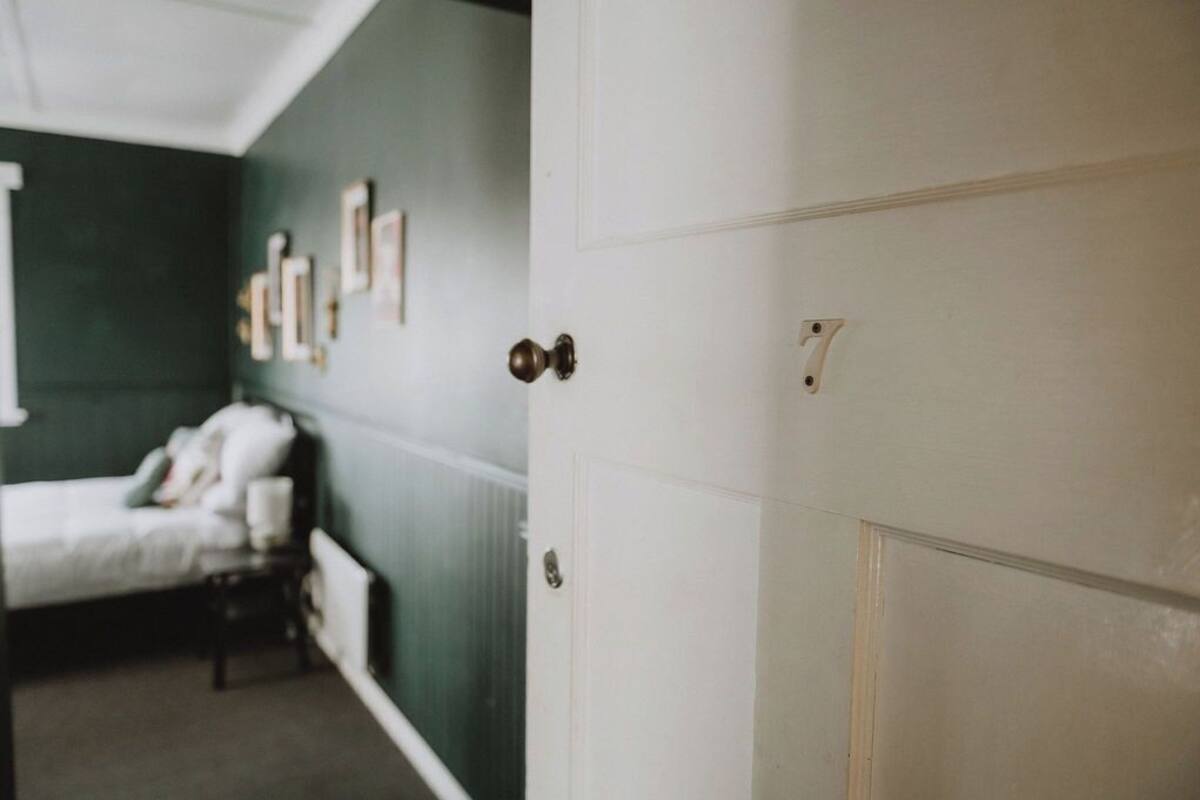 A room with a bed, a door, and wall-mounted pictures.