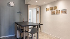 Eine moderne Küche mit dunkler Arbeitsplatte, Barhocker und einer Uhr an der Wand.