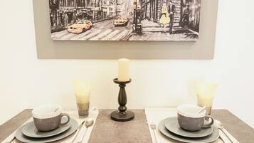 Una mesa de comedor dispuesta con dos tazas, una vela y cubiertos.