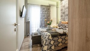 Ein Schlafzimmer mit einem Bett, einem Nachttisch und einem an der Wand befestigten Fernseher.