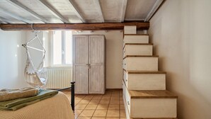 Una stanza con una scala in legno, un armadio e un'amaca.