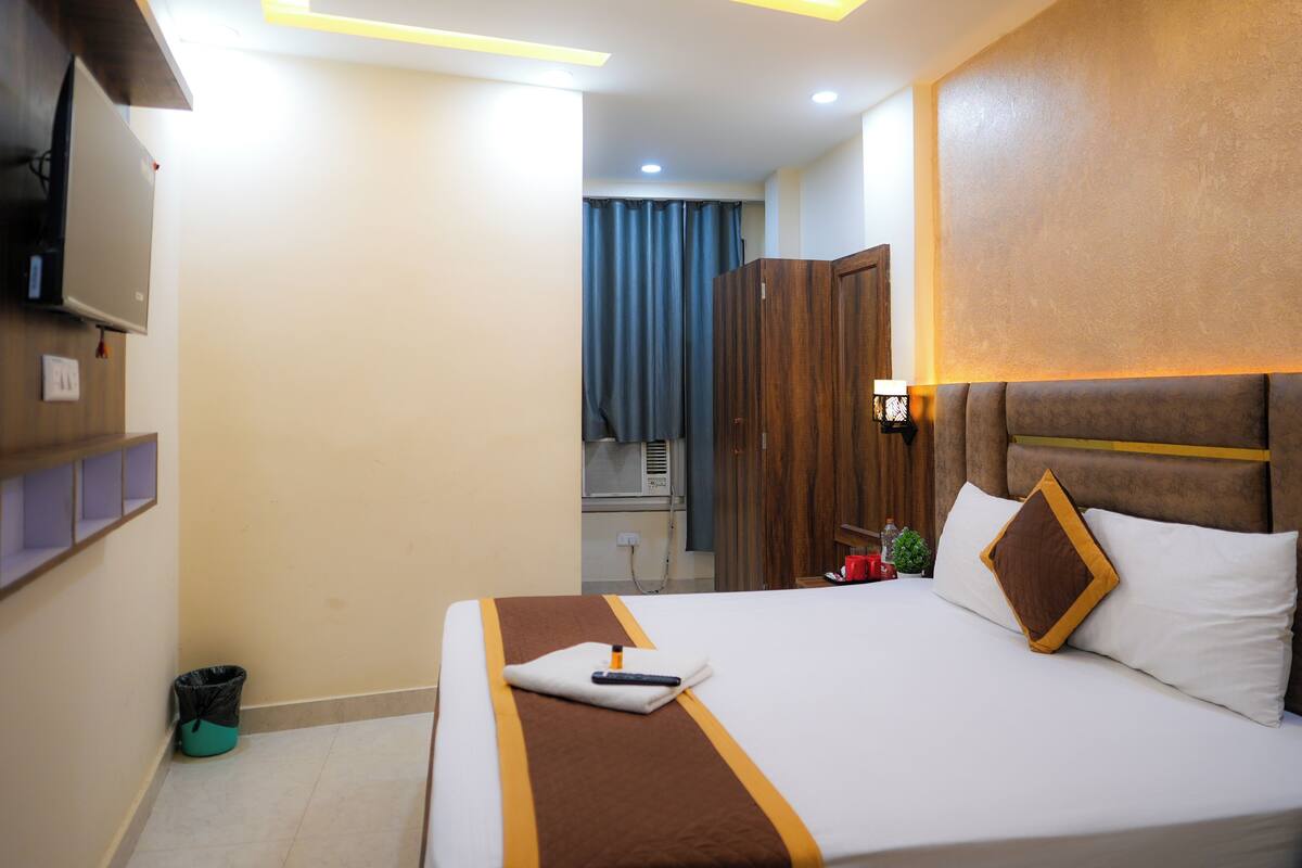 A hotel room with a bed, a TV mounted on the wall, and a ceiling light fixture.
