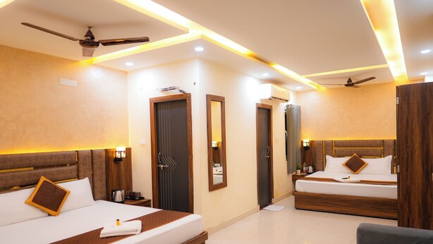 Een hotelkamer met twee bedden, een bank, plafondventilatoren en moderne verlichting.