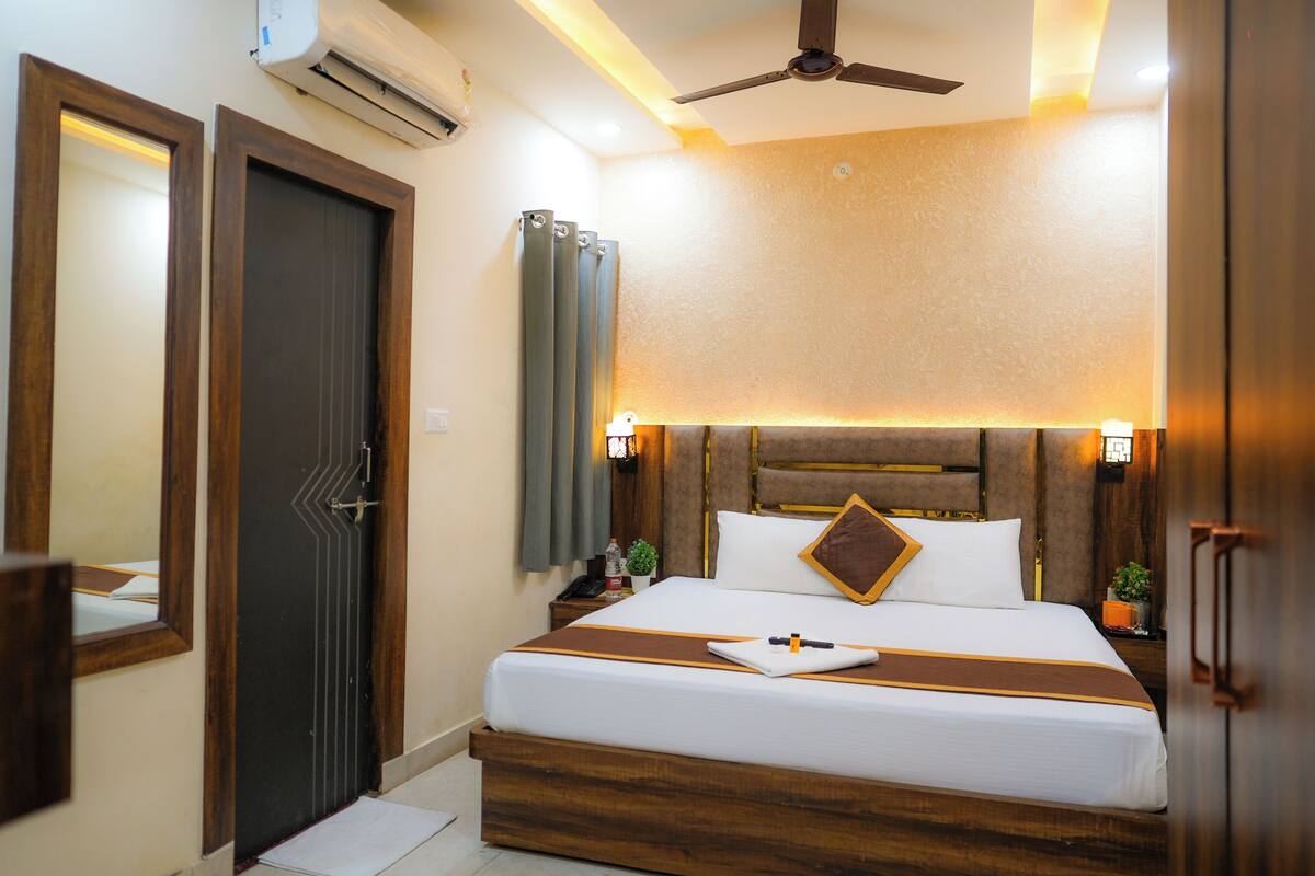 A hotel room with a bed, bedside tables, a ceiling fan, and an air conditioning unit.