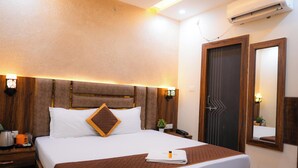 Hotelkamer met groot bed, houten hoofdbord, nachtkastjes, een airconditioning en een spiegel, met een deur met een geometrisch patroon.