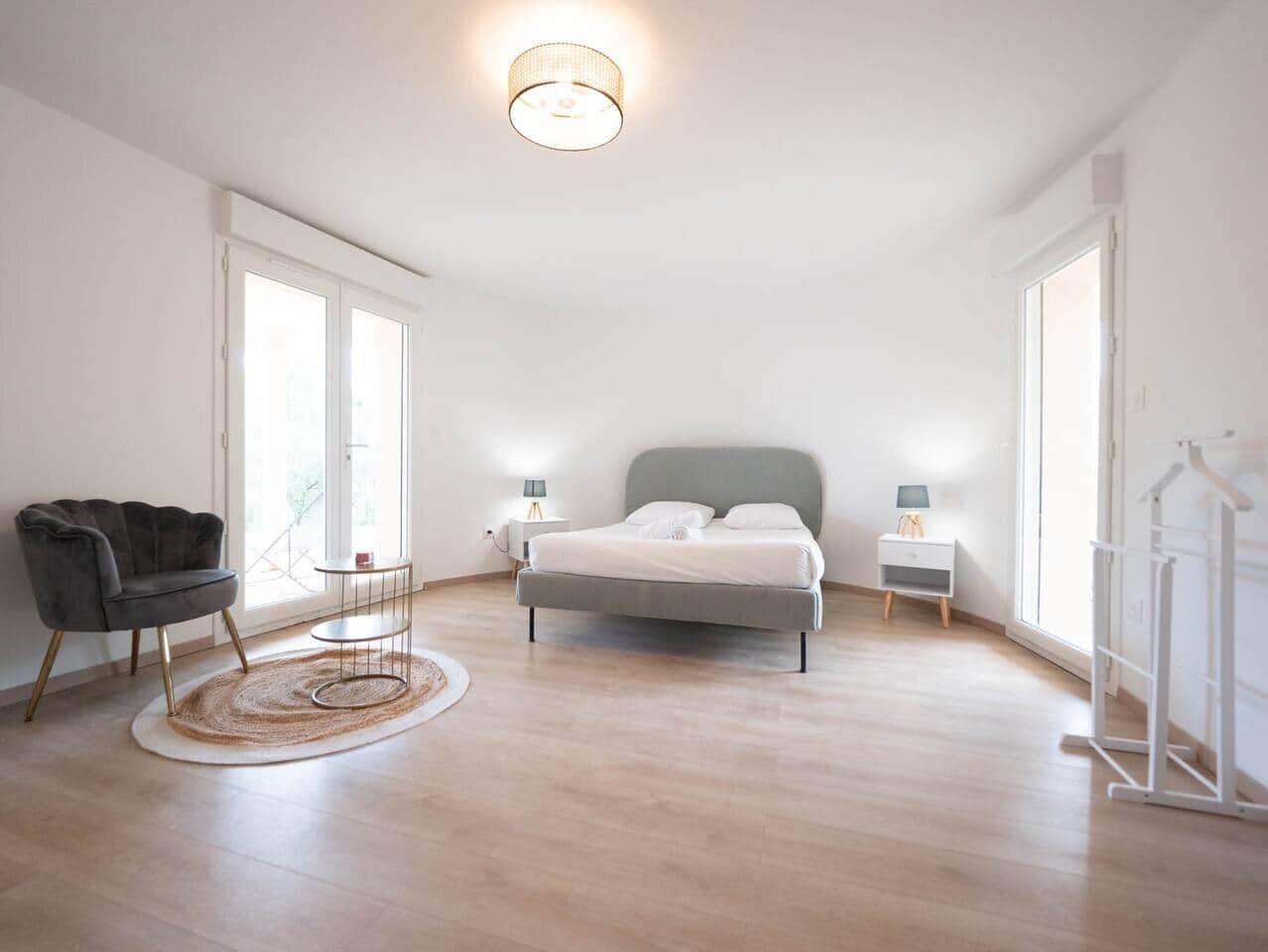 Une chambre spacieuse avec un grand lit, une chaise, une table de chevet et une armoire.