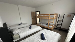 A dormitory room with three bunk beds, a wardrobe, and a clothing rack. - Au 8 Duplexe du coin (Flémalle)