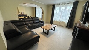 A living room with a sectional sofa, a coffee table, and a TV. - Au 8 Duplexe du coin (Flémalle)