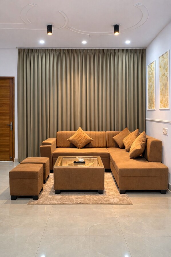 A modern living room with a sectional sofa, ottomans, and a glass coffee table.