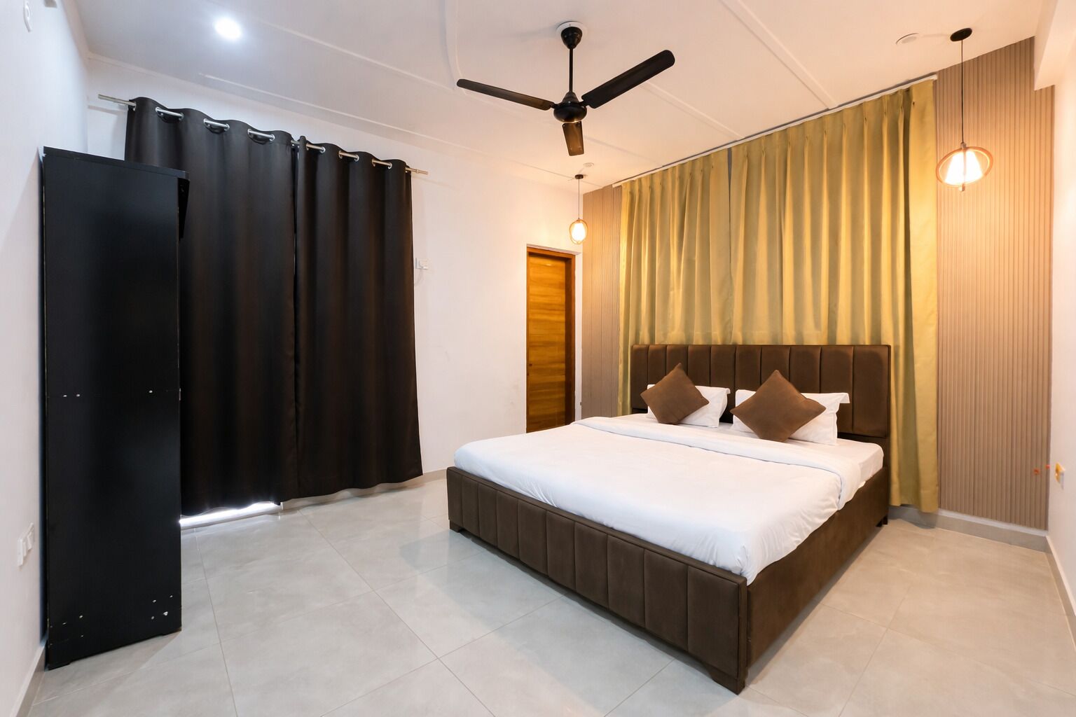 Une chambre à coucher avec un lit, des rideaux, un ventilateur de plafond et un luminaire.
