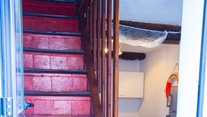 Un escalier aux marches rouges mène à une pièce où se trouvent une table à manger et des chaises.