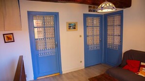 Une pièce avec deux portes bleues, un banc en bois, un canapé et un luminaire suspendu.
