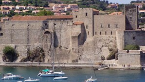Une forteresse historique en pierre, dotée d’un fossé et de bateaux, qui surplombe une ville aux maisons à étages.