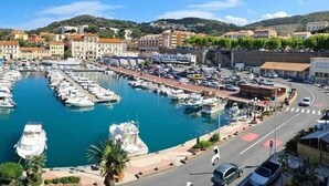 Un port de plaisance où sont amarrés de nombreux bateaux, entouré de bâtiments et avec un paysage vallonné en arrière-plan.