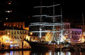 Ein historisches Segelschiff liegt im Hafen vor einer Gebäudereihe.