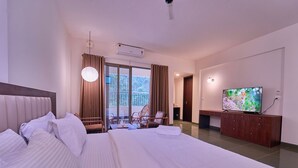 Ein Hotelzimmer mit einem großen Bett, einem Fernseher, einem Holzkabinett und einem Balkon mit Vorhängen.