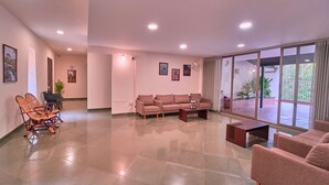 A spacious living room with a large sofa set, a coffee table, and a dining area with chairs. - Achutham Banasura villa by VOYE HOMES (Vythiri)
