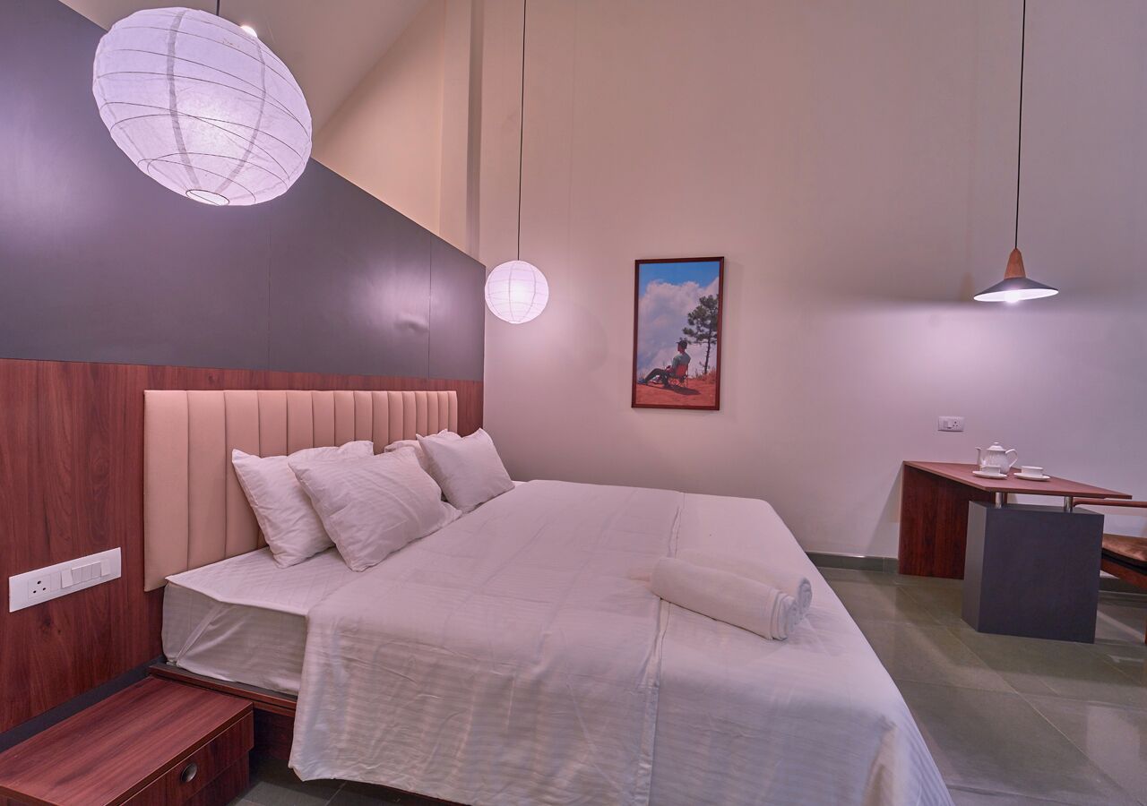 Ein modernes Schlafzimmer mit einem großen Bett, Nachttischen, einem Schreibtisch und einer Pendelleuchte.