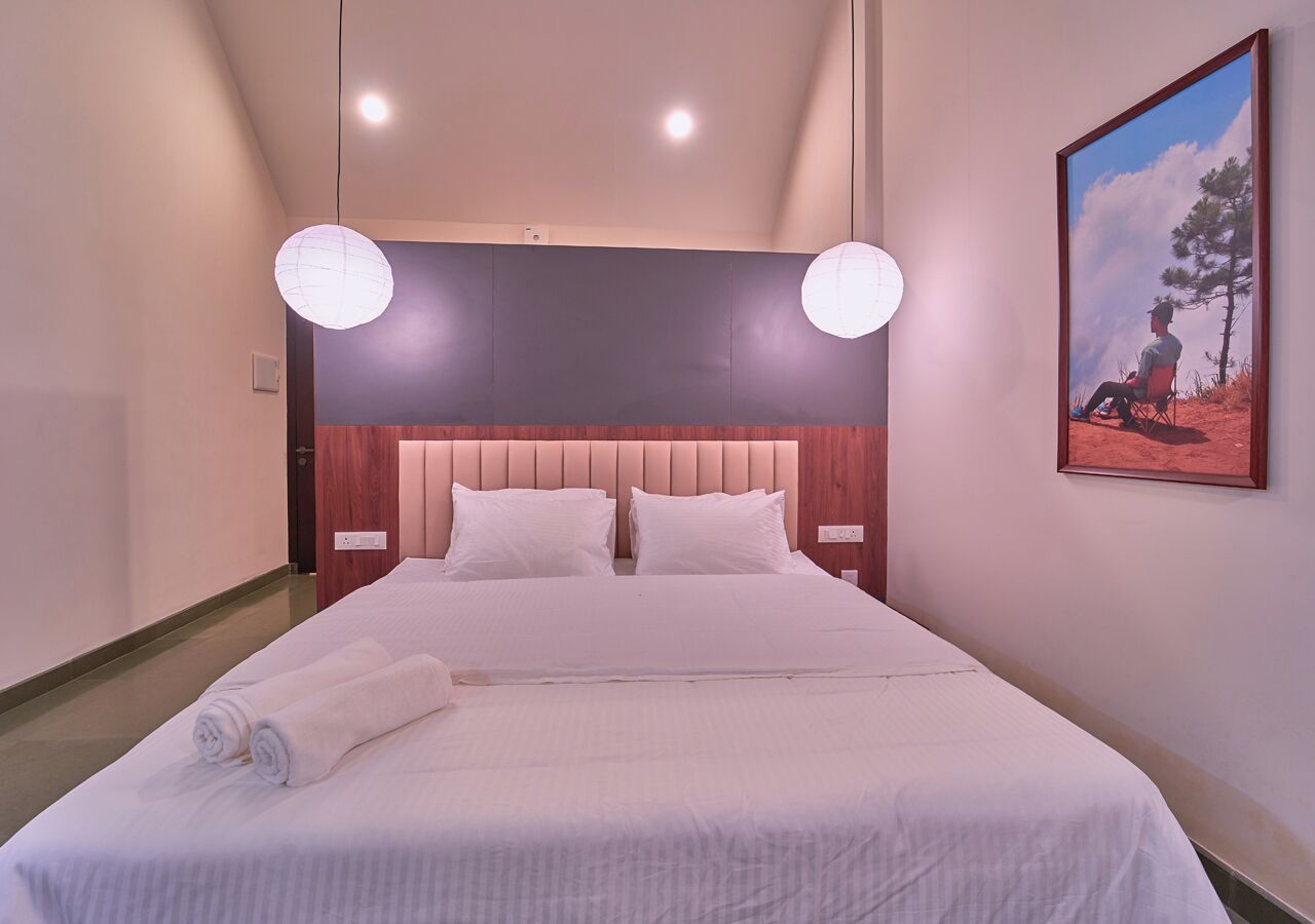 A hotel room with a large bed, two bedside tables, a headboard, and a painting on the wall.